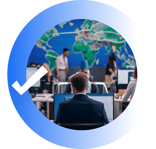 Photo of a person at a computer screen. In front of him people are talking in front of a map of the world.