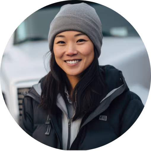 smiling worker in a coat and beanie standing in front of a truck