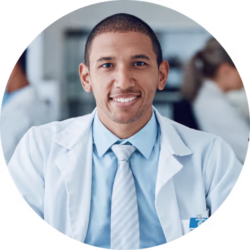 A man in a white coat and blue tie smiling