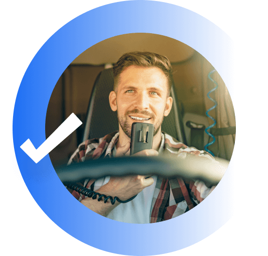 A man smiling and talking into a microphone. while driving a truck