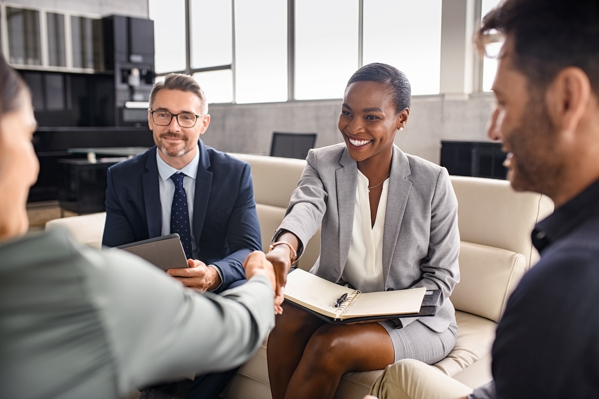 A group of employees in a meeting, shaking hands.