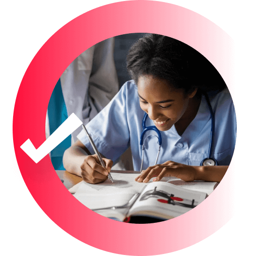 A student in scrubs smiling while studying textbooks.