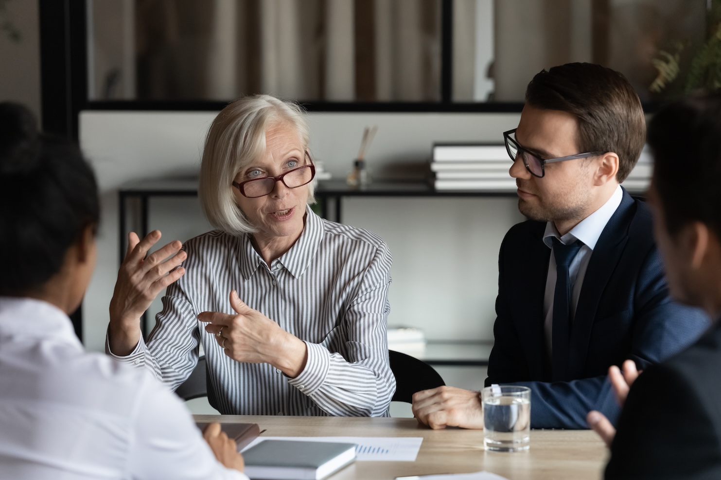 senior business leader speaking during a meeting with colleagues around a conference table