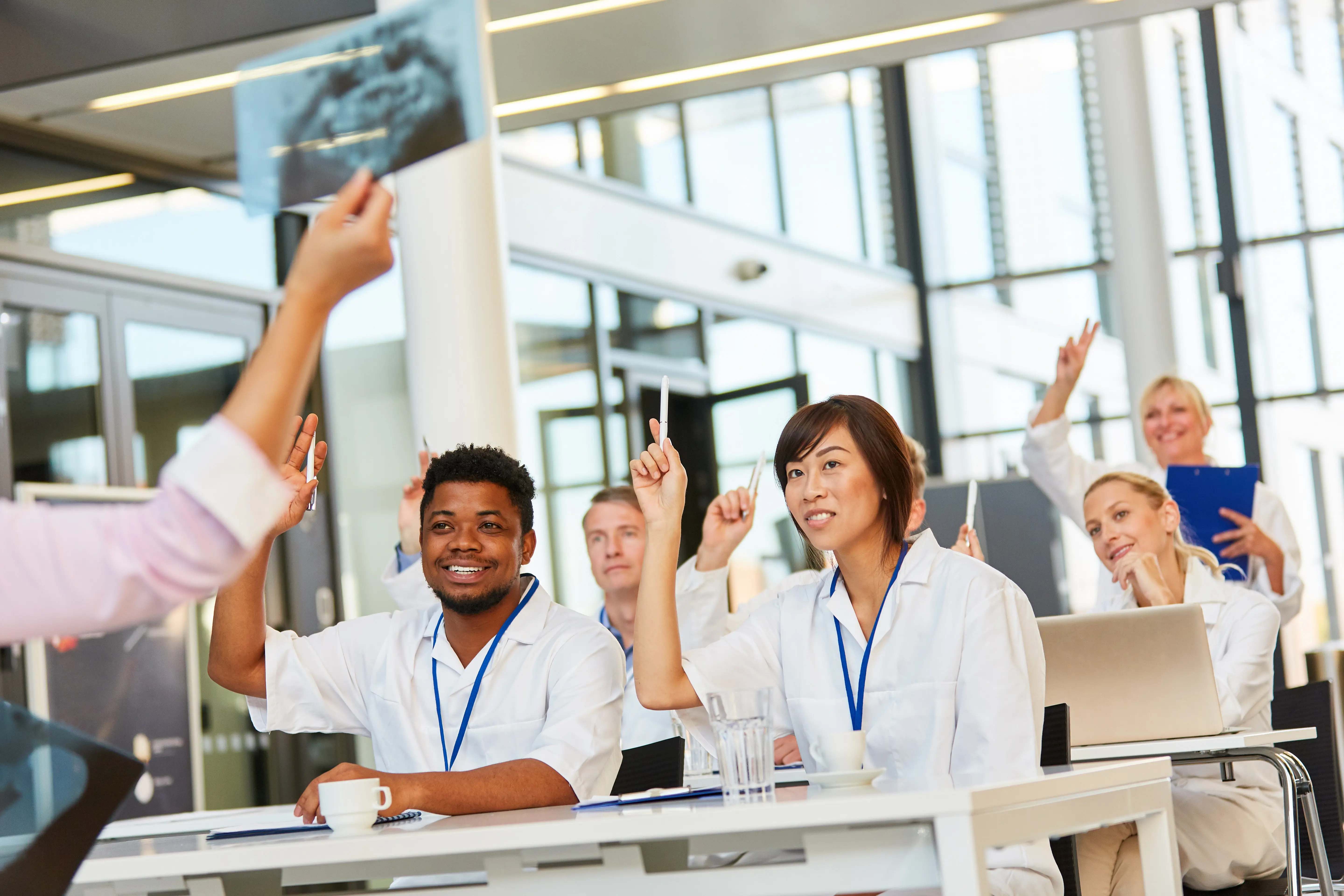 Employees in a meeting, all smiling with hands help up in the air.