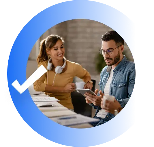 coworkers collaborating casually with a tablet inside a blue circle with a checkmark