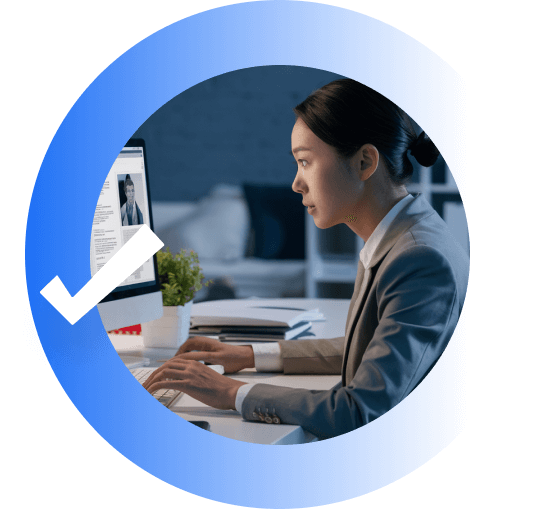 Business professional reviewing a profile on a desktop computer, shown within a blue circular graphic with a white checkmark.