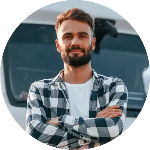 confident man standing with arms crossed in front of a truck